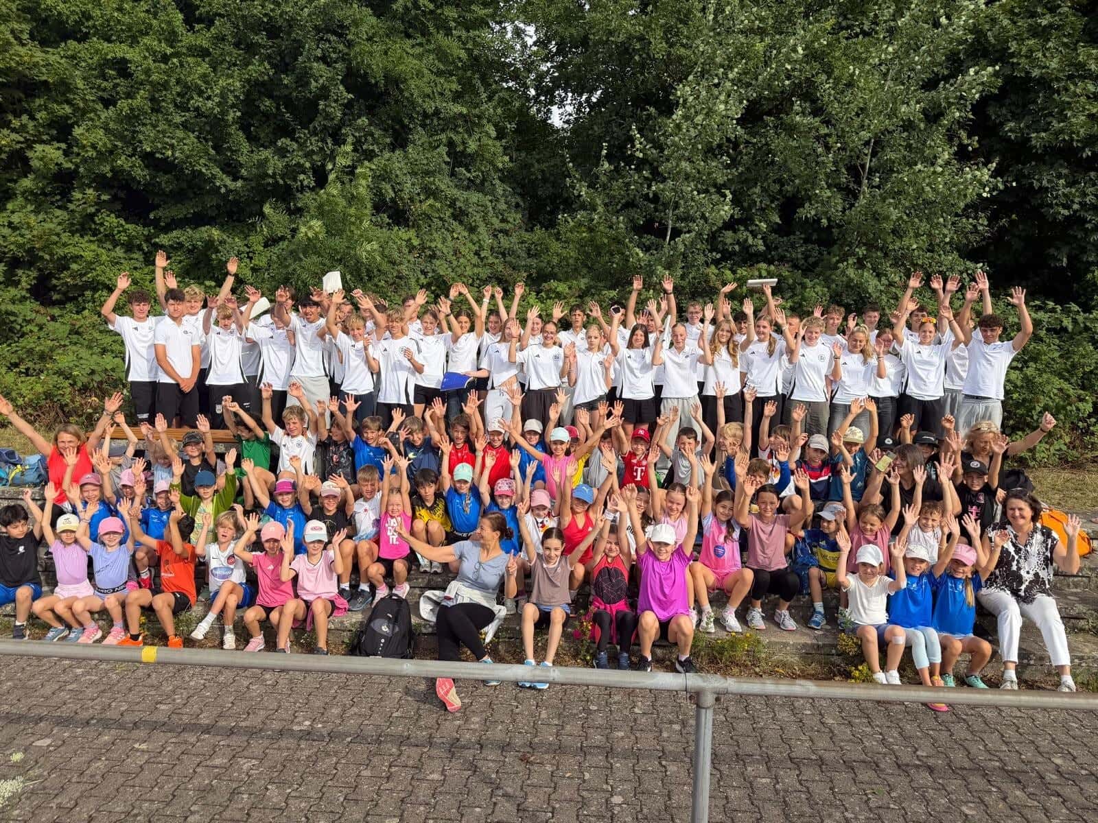 Bundesjugendspiele 2026 - Alle Schülerinnen und Schüler winken beim gemeinsamen Gruppenfoto mit den Sportmentoren des Anna-Essinger-Gymnasiums