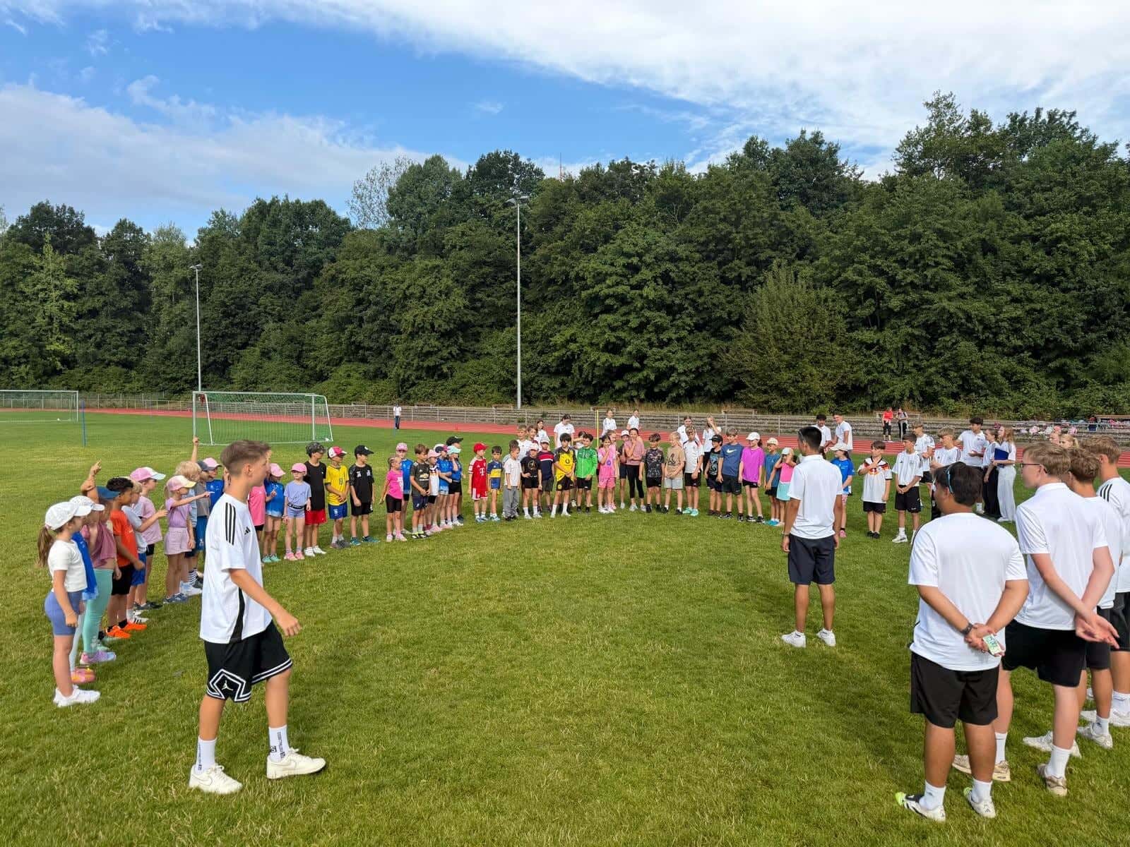 Bundesjugendspiele 2026 - Kinder und Sportmentoren beim gemeinsamen Spiel auf dem Sportplatz