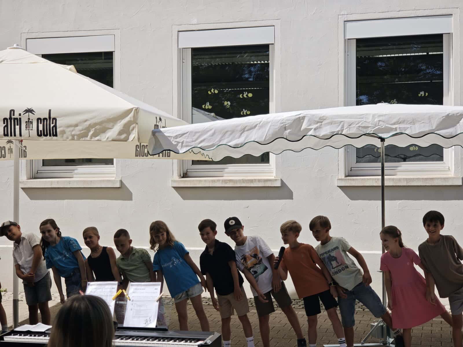 Schulfest 2026 - Kinder tragen am Klavier gemeinsam ein Gedicht auf dem Schulhof vor