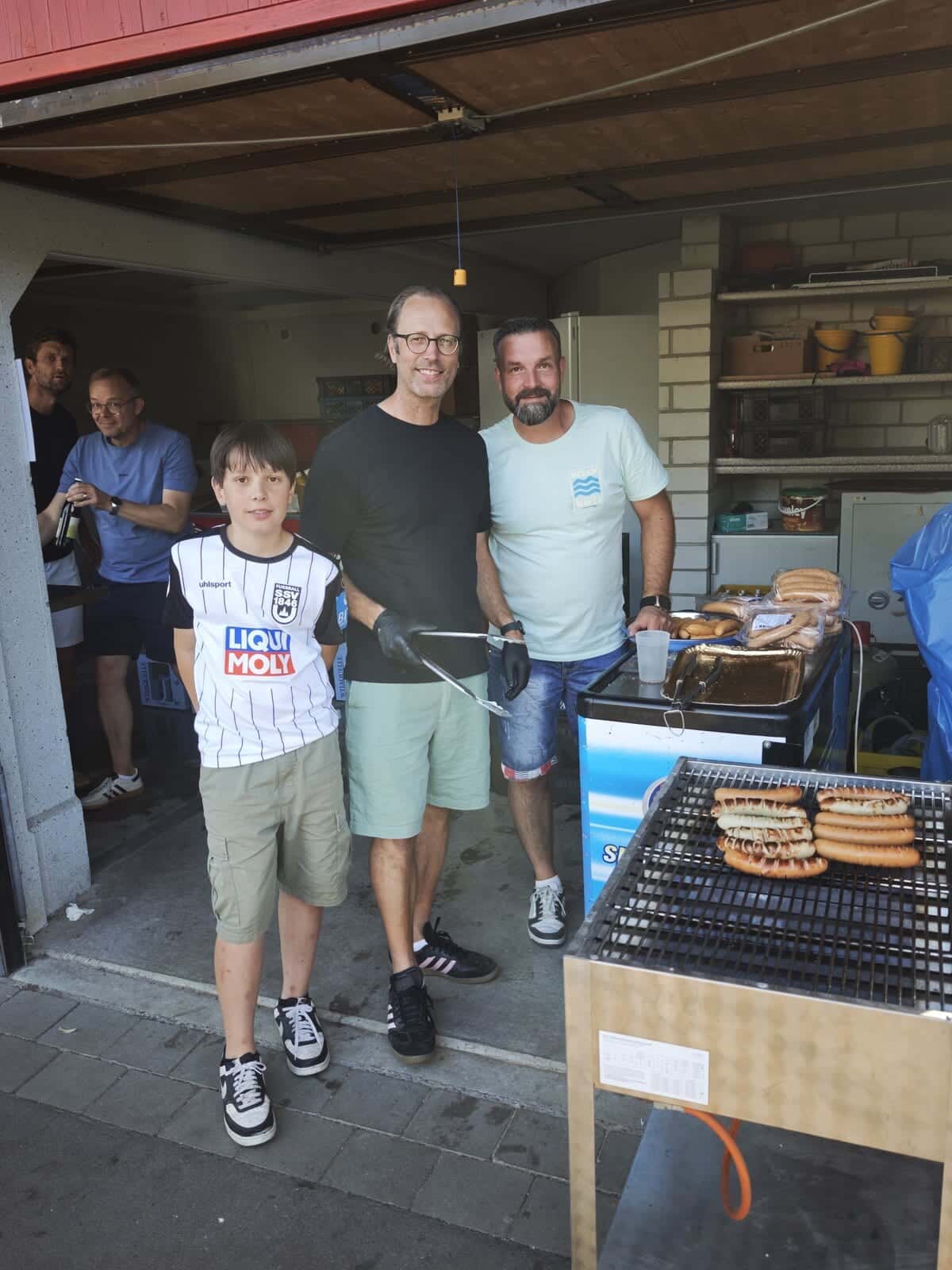 Schulfest 2026 - Helfer am Grill versorgen die Gäste bei der Hockete mit Roten Würsten