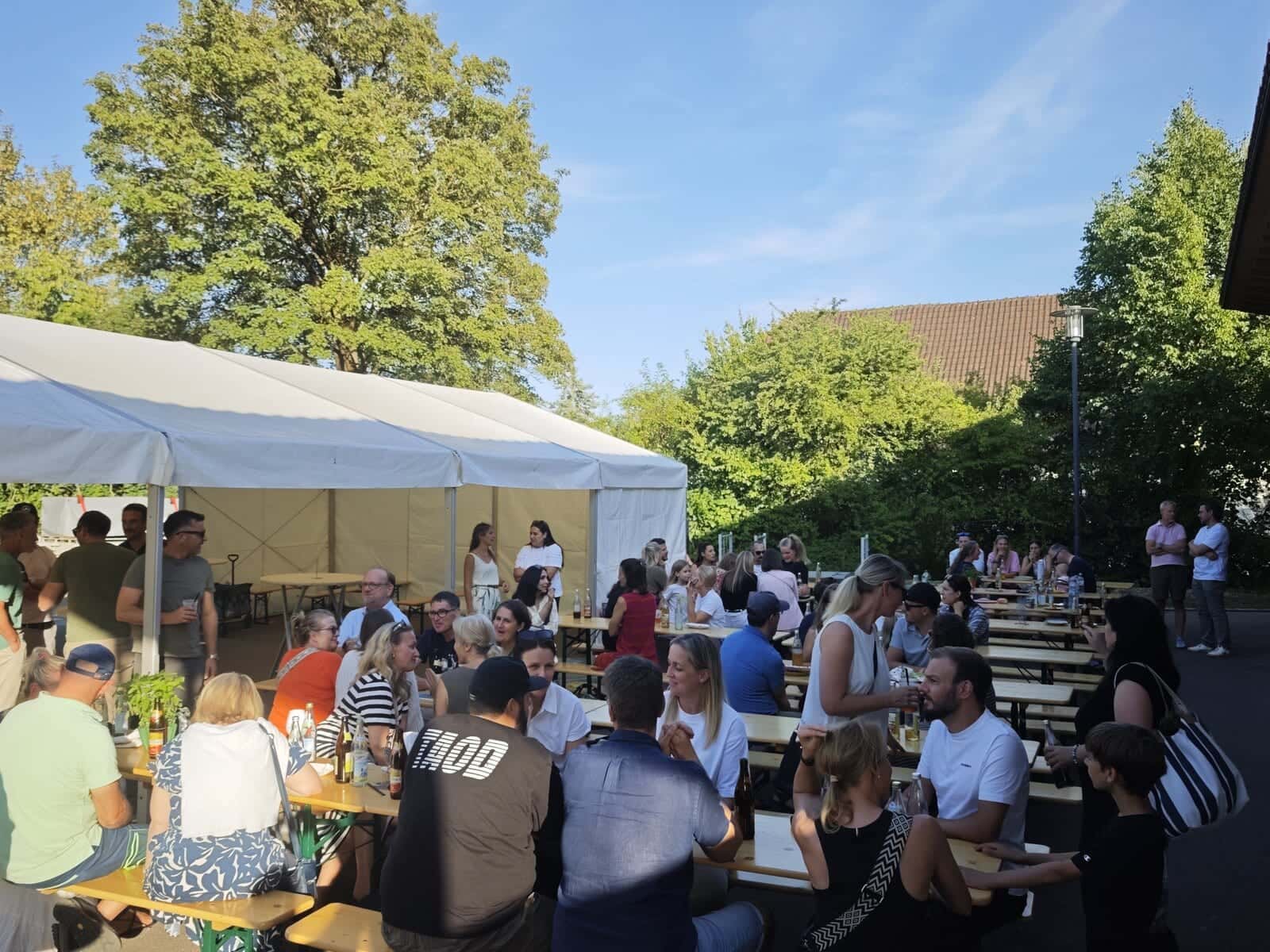 Schulfest 2026 - Gäste sitzen bei der Hockete an Biertischgarnituren auf dem Dorfplatz