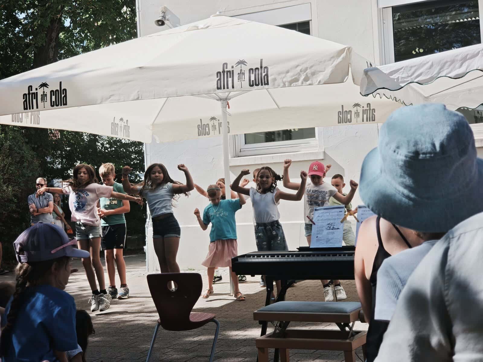 Schulfest 2026 - Schülerinnen und Schüler tanzen vor dem Publikum unter den Sonnenschirmen