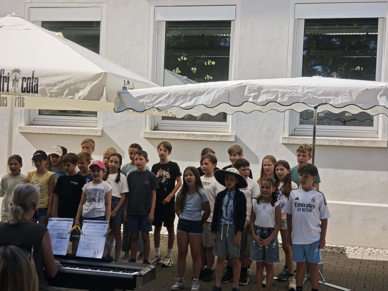 Schulfest 2026 - Große Kindergruppe singt zur Klavierbegleitung auf dem Schulhof
