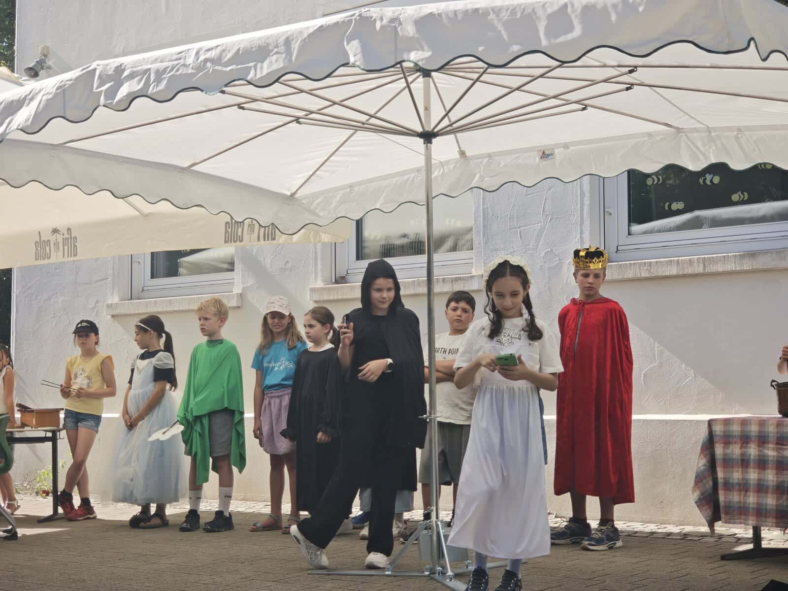 Schulfest 2026 - Szene aus dem Theaterstück mit König im roten Umhang und Kindern in weißen Gewändern