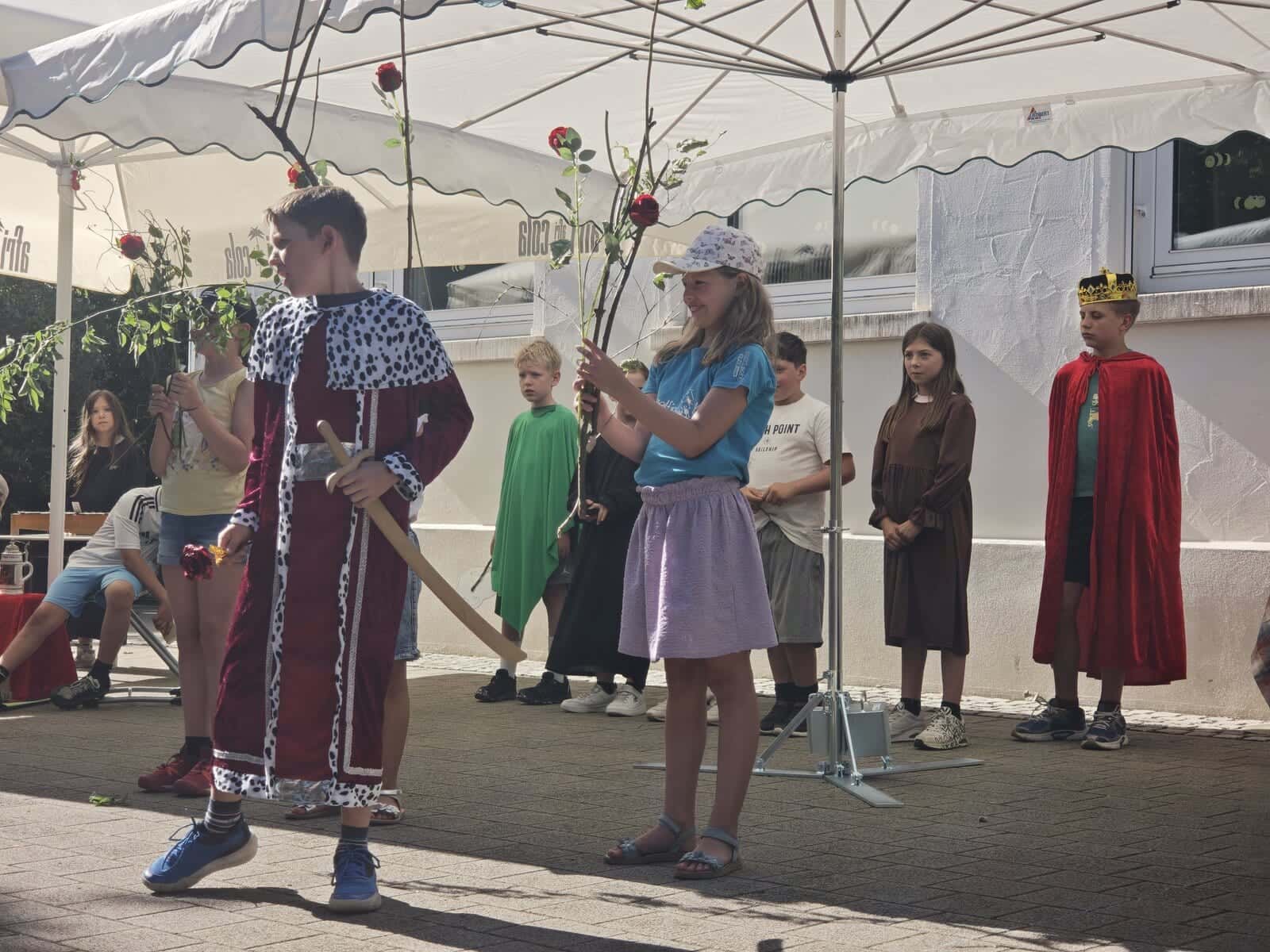 Schulfest 2026 - Theaterszene mit Kind im Hermelinmantel und Rosenzweigen als Requisiten