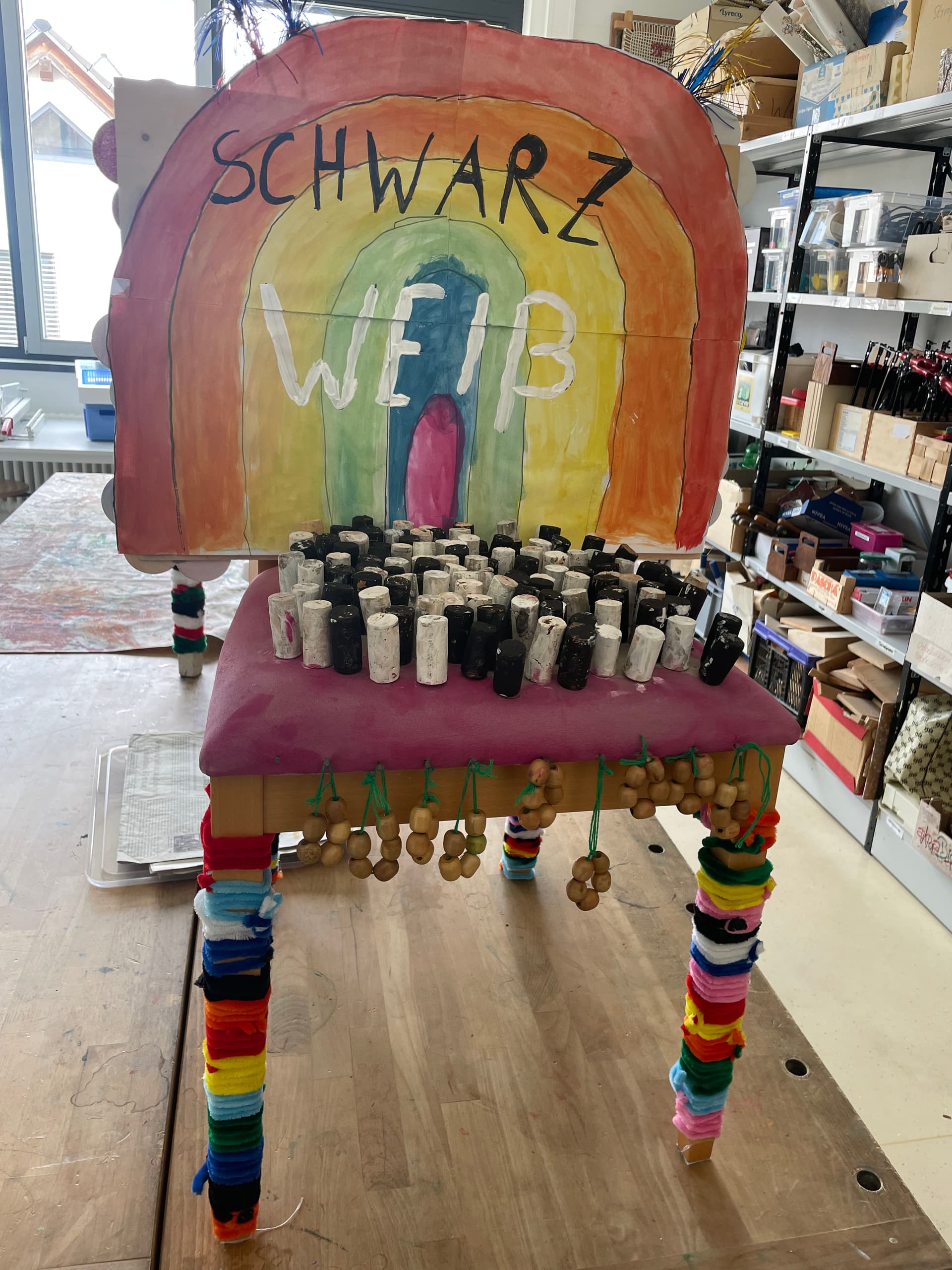 Stuhl-Projekt 2026 - Stuhl mit Regenbogen-Lehne Schwarz Weiß und bunten Figurengruppen
