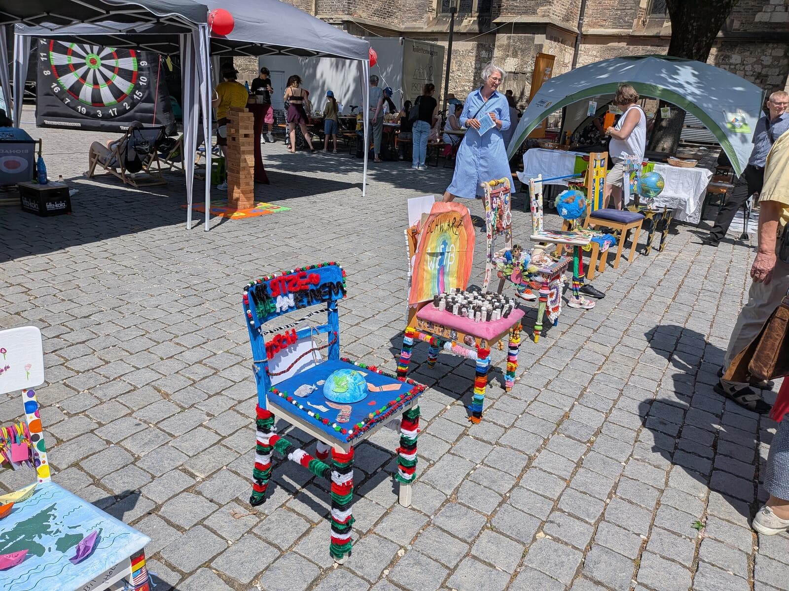 Wir sitzen alle an einem Tisch 2026 - Bunt gestaltete Schülerstühle auf dem Münsterplatz, im Vordergrund ein Stuhl mit aufgemaltem Globus